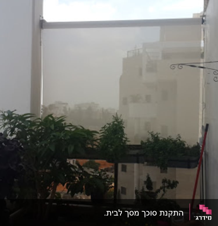 Awnings on a balcony with plants and a view of buildings.